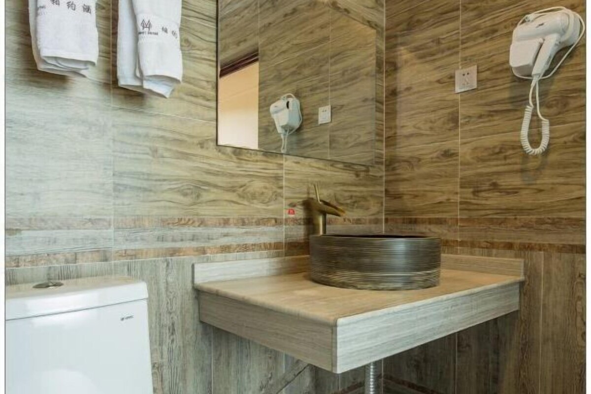 Un baño con tocador de madera, un lavabo redondo y un espejo.