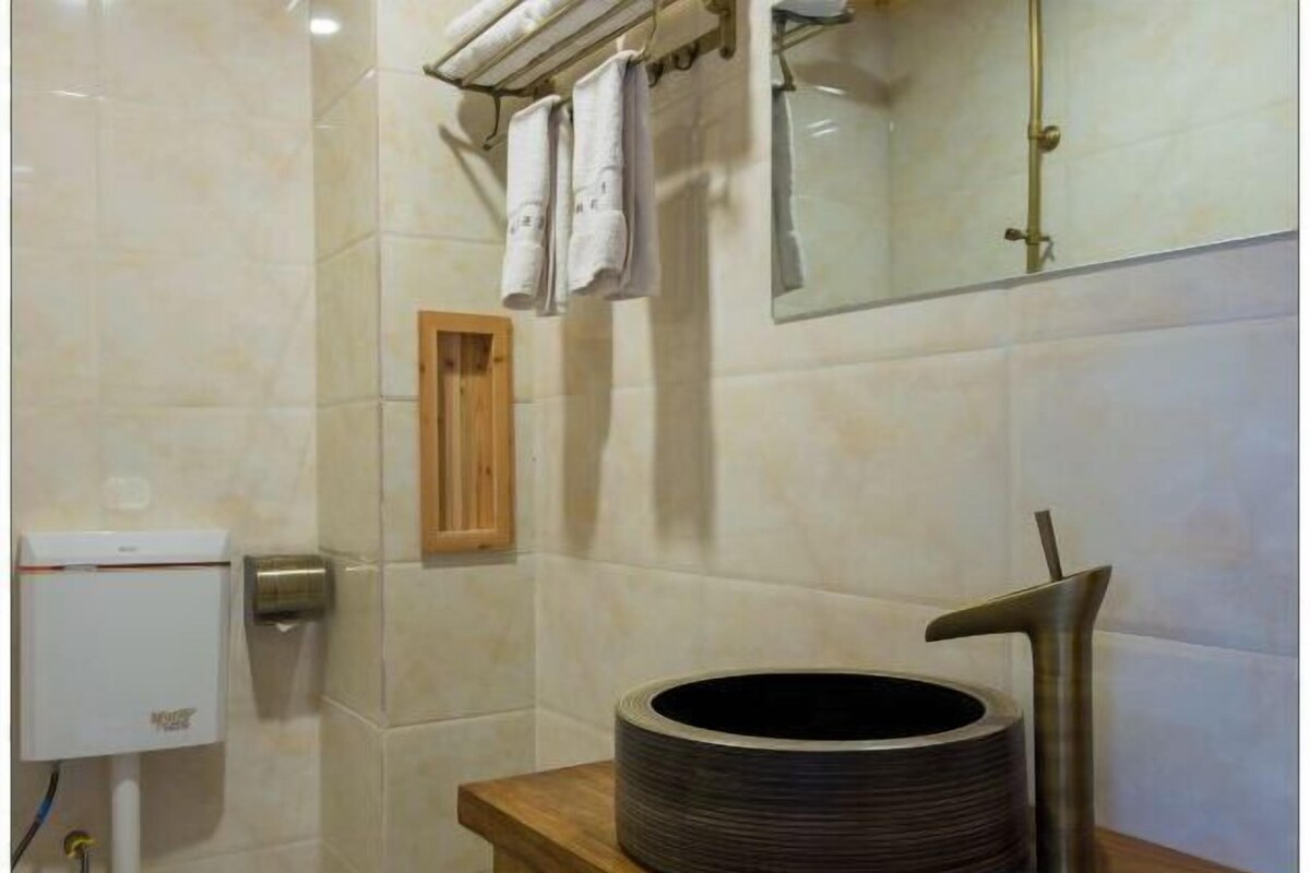Un baño con inodoro, lavamanos con grifo moderno y espejo.