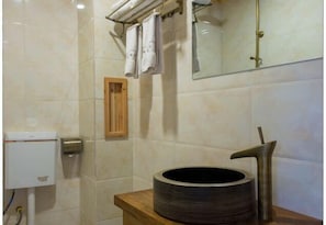 Un baño con inodoro, lavamanos con grifo moderno y espejo.