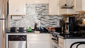 A modern kitchen with white cabinets, a stainless steel refrigerator, a dishwasher, a microwave, and a stove. - Condo On The Beach - Ocean Side View Balcony (Belleair Beach)