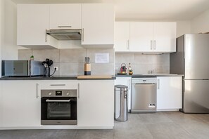 A modern kitchen with white cabinets, stainless steel appliances, and a built-in oven.
