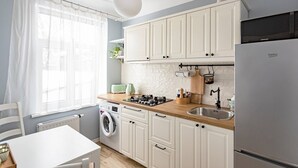 A modern kitchen with white cabinets, a wooden countertop, a built-in washing machine, and a stainless steel sink. - Vintage Apartments Blue / Free parking (Rīga)