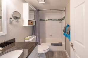 Une salle de bain compacte avec des toilettes blanches, une baignoire et un espace douche.