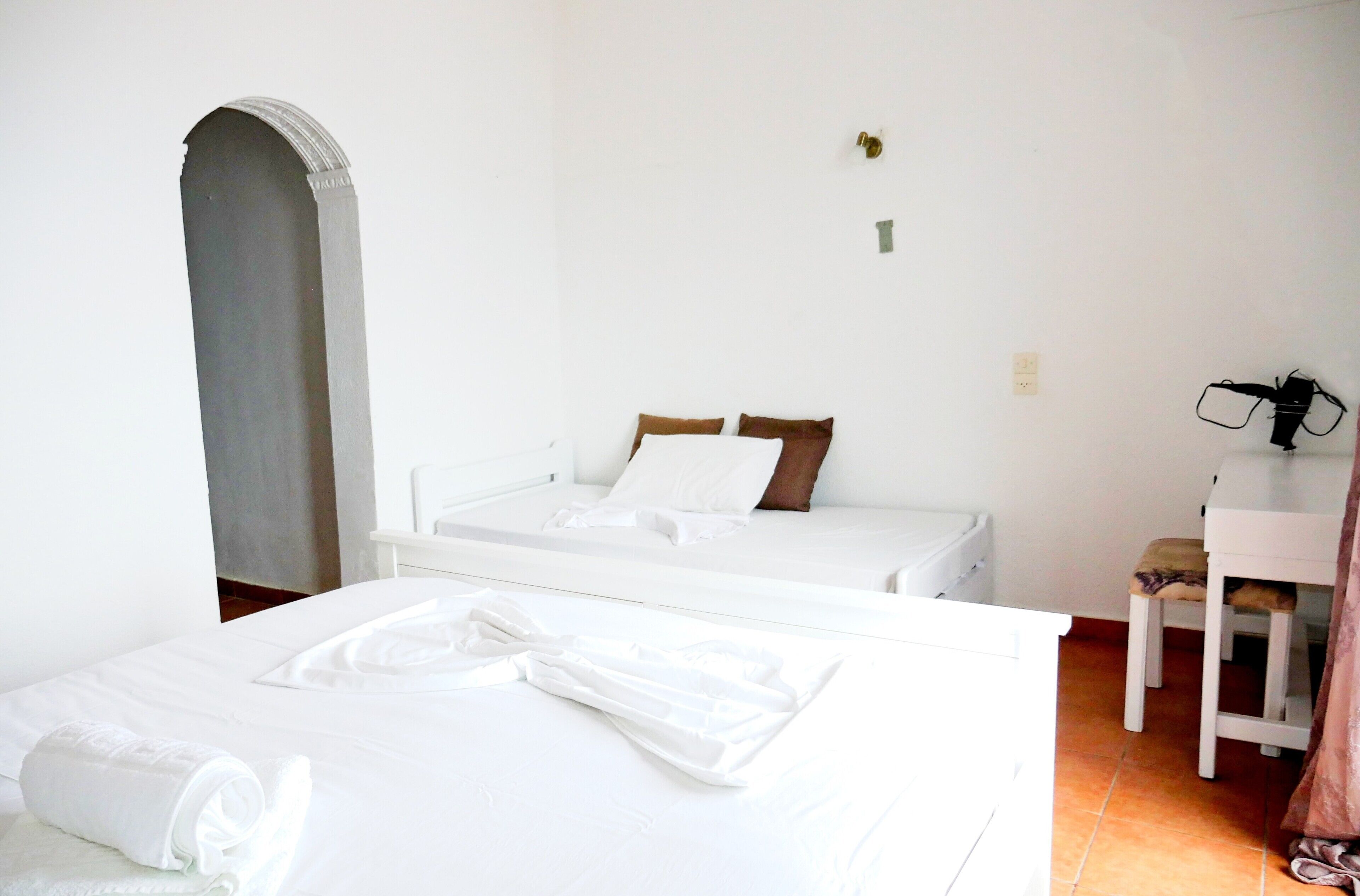 Ein Hotelzimmer mit zwei Betten, einem kleinen Schreibtisch und einem Stuhl.