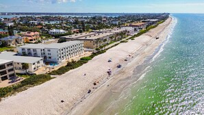 A beachfront hotel with multiple buildings, a sandy beach, and a view of the ocean.