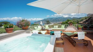 Una terrazza sul tetto con idromassaggio, poltrone relax e piante in vaso.