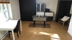 A room with a foosball table, a white desk, a chair, and a window.