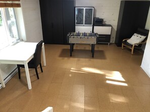 A room with a foosball table, a white desk, a chair, and a window.