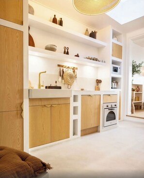 A modern kitchen with white cabinetry, wooden accents, and a built-in oven.