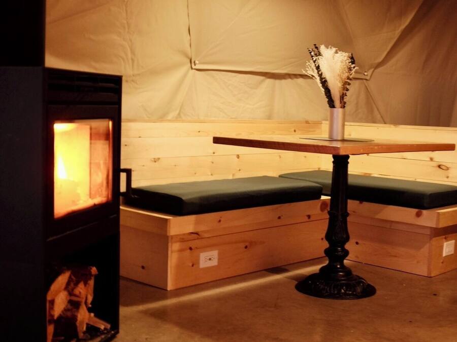 A cozy room with a wooden bench, a small table with a vase, and a fireplace.