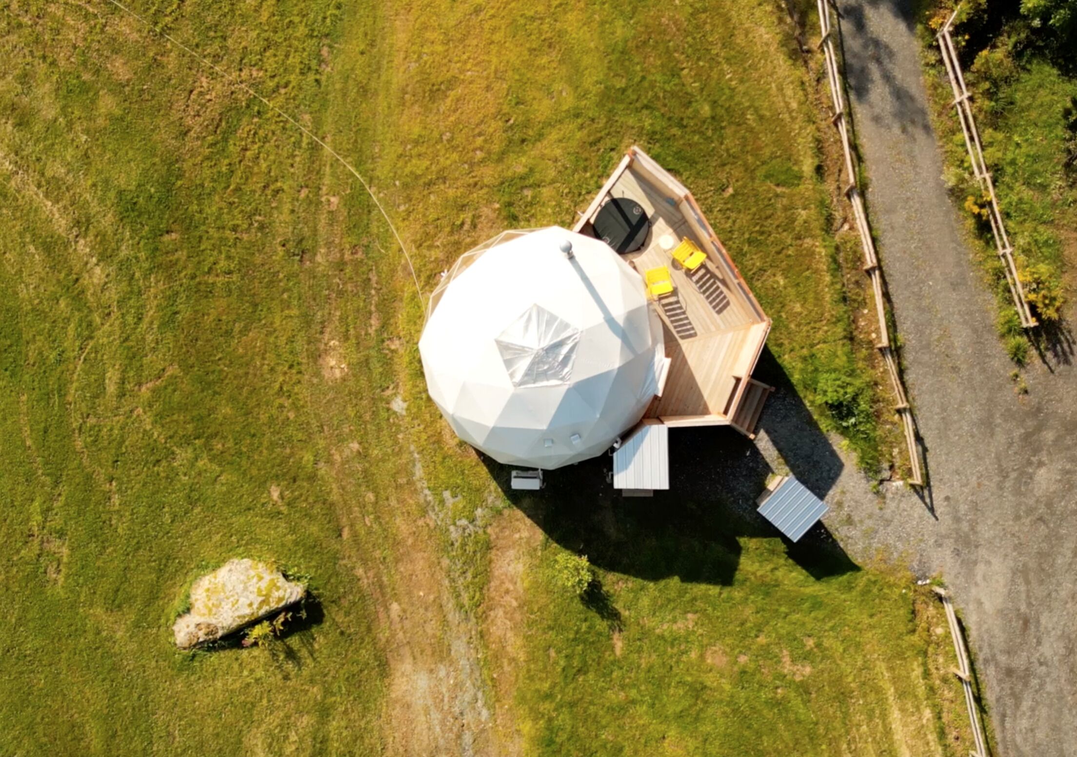 Vista aérea de una estructura de cúpula geodésica con terraza y zona de estar.