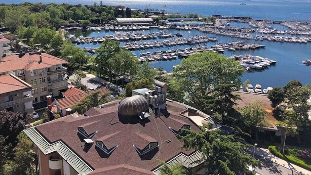 A marina with numerous boats docked, surrounded by residential buildings and greenery. - Petek Pansiyon (Istanbul)