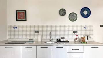 Una cocina moderna con armarios blancos, un lavamanos de acero inoxidable y un protector contra salpicaduras de azulejos.
