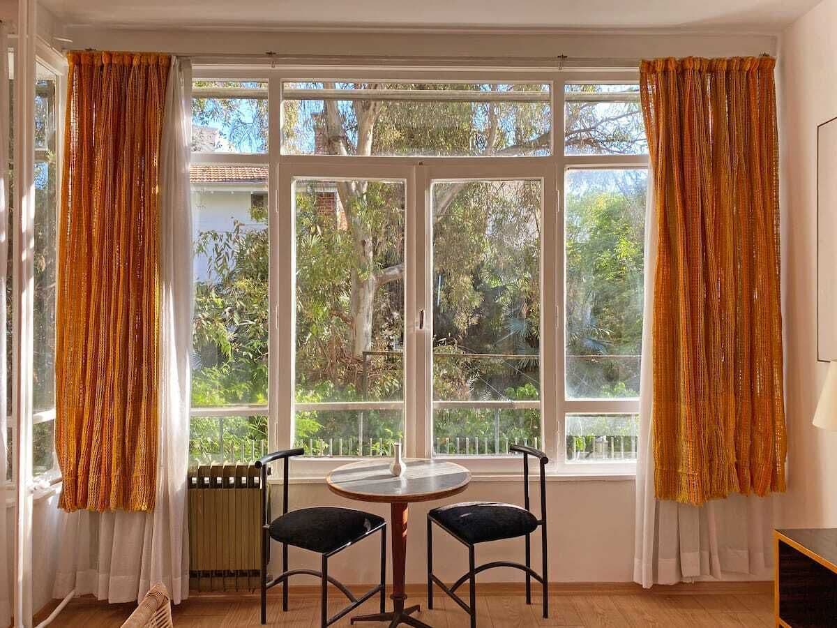 A room with a large window, two chairs, a small table, and a radiator.