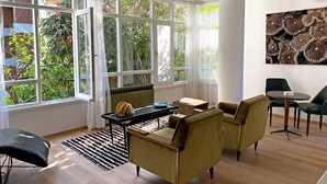 A spacious living room with large windows, a black and white rug, and a table with chairs. - Petek Pansiyon (Istanbul)