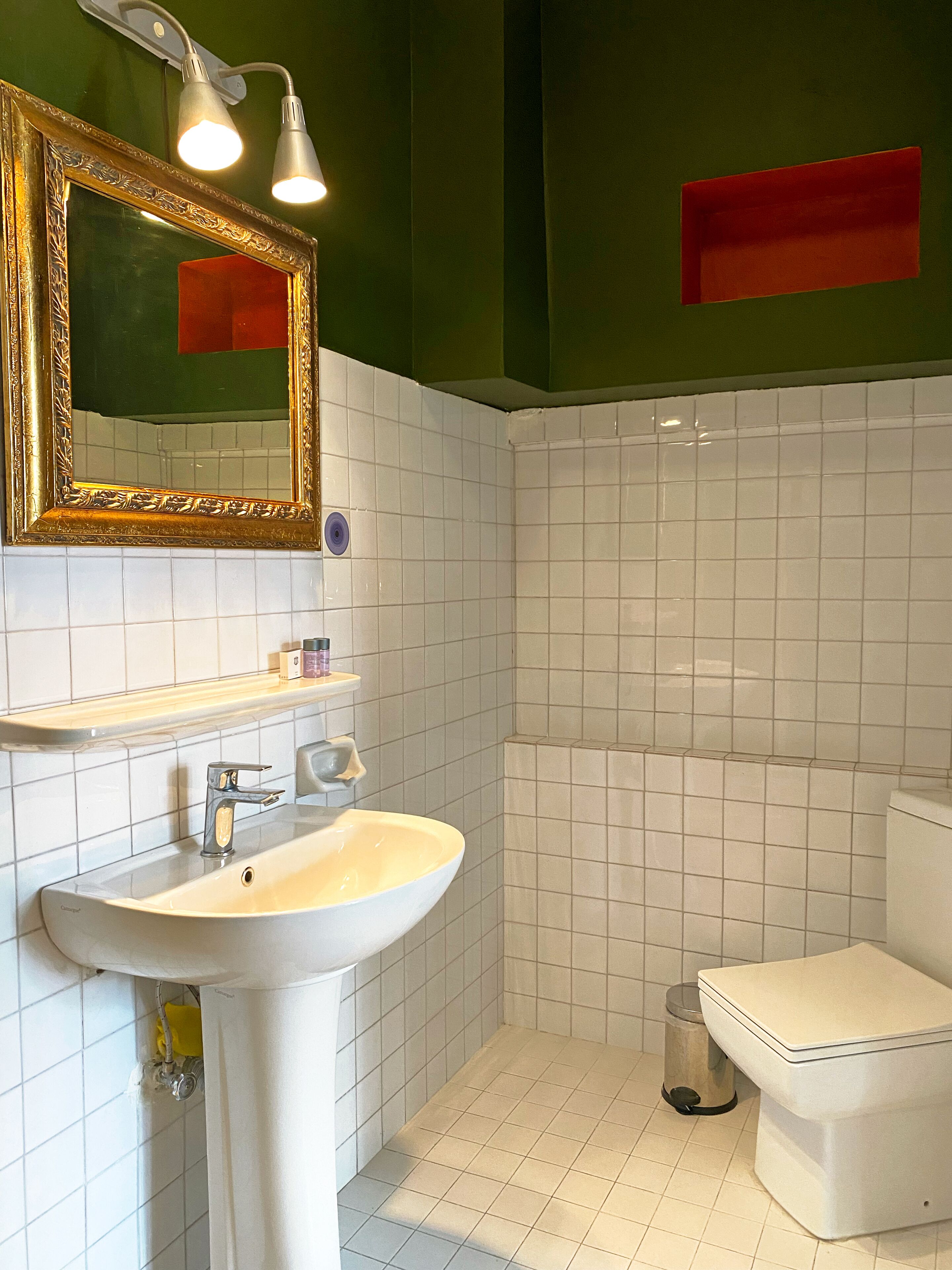 A bathroom with a white sink, a toilet, and a mirror with lights.