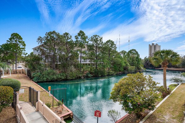 A riverside view with a bridge, trees, and buildings.