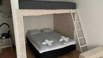 A bunk bed with a wooden ladder, a small bedside table, and a chair.