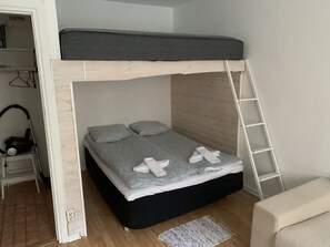 A bunk bed with a wooden ladder, a small bedside table, and a chair.
