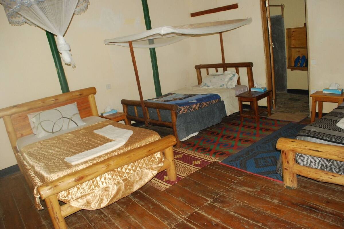 A room with two wooden beds, a small table, and a chair.