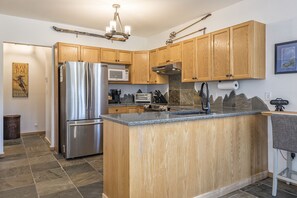 Una cocina moderna con armarios de madera, electrodomésticos de acero inoxidable y encimera de granito.