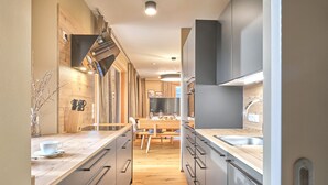 Eine moderne Küche mit Holzboden, grauen Schränken und einer zentralen Kochinsel.
