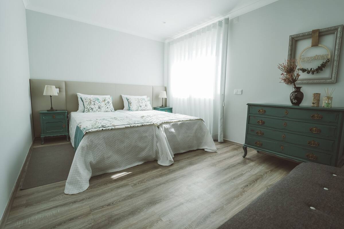 Ein Schlafzimmer mit einem Bett, Nachttischen, einer Kommode und einem Spiegel an der Wand.