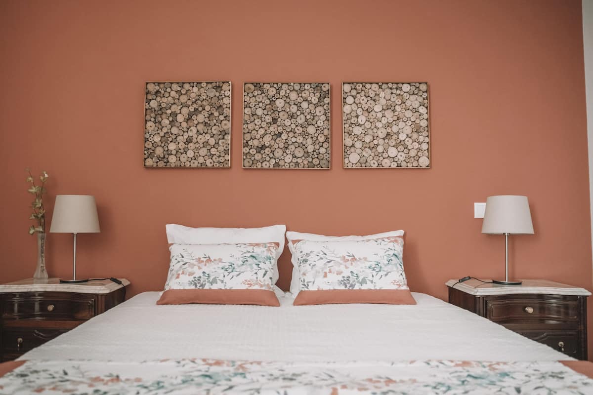 Ein Schlafzimmer mit einem Bett, zwei Nachttischen und drei an der Wand befestigten Bilderrahmen.