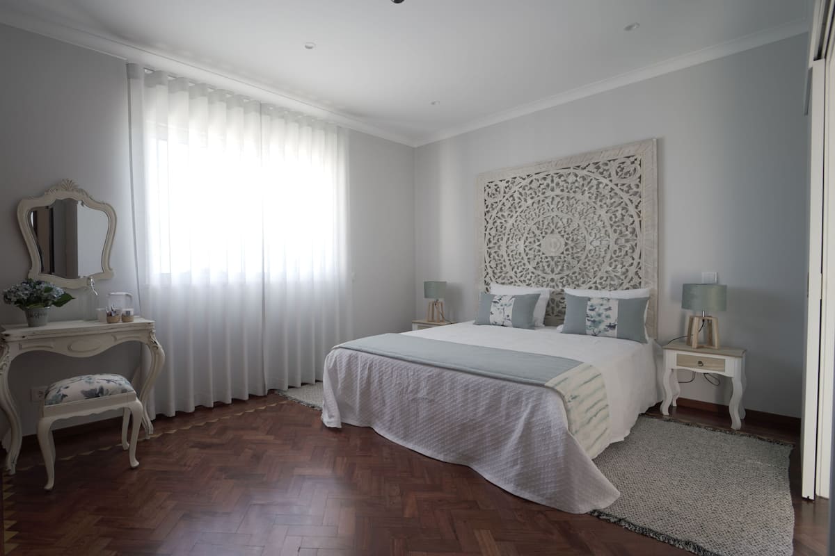 Ein Schlafzimmer mit einem großen Bett, einem Schminktisch mit Spiegel und einem dekorativen Kopfteil.
