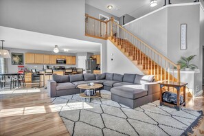 Relax in a spacious living area with a large sofa, coffee table, and rug. Enjoy meals in the dining area with a table and chairs.