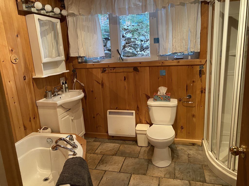 Une salle de bain avec un intérieur en bois, un lavabo blanc, une baignoire, des toilettes et un espace douche.