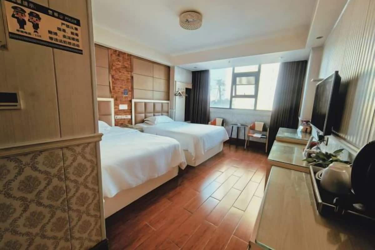 Habitación de hotel con dos camas, un escritorio, un televisor y una ventana.