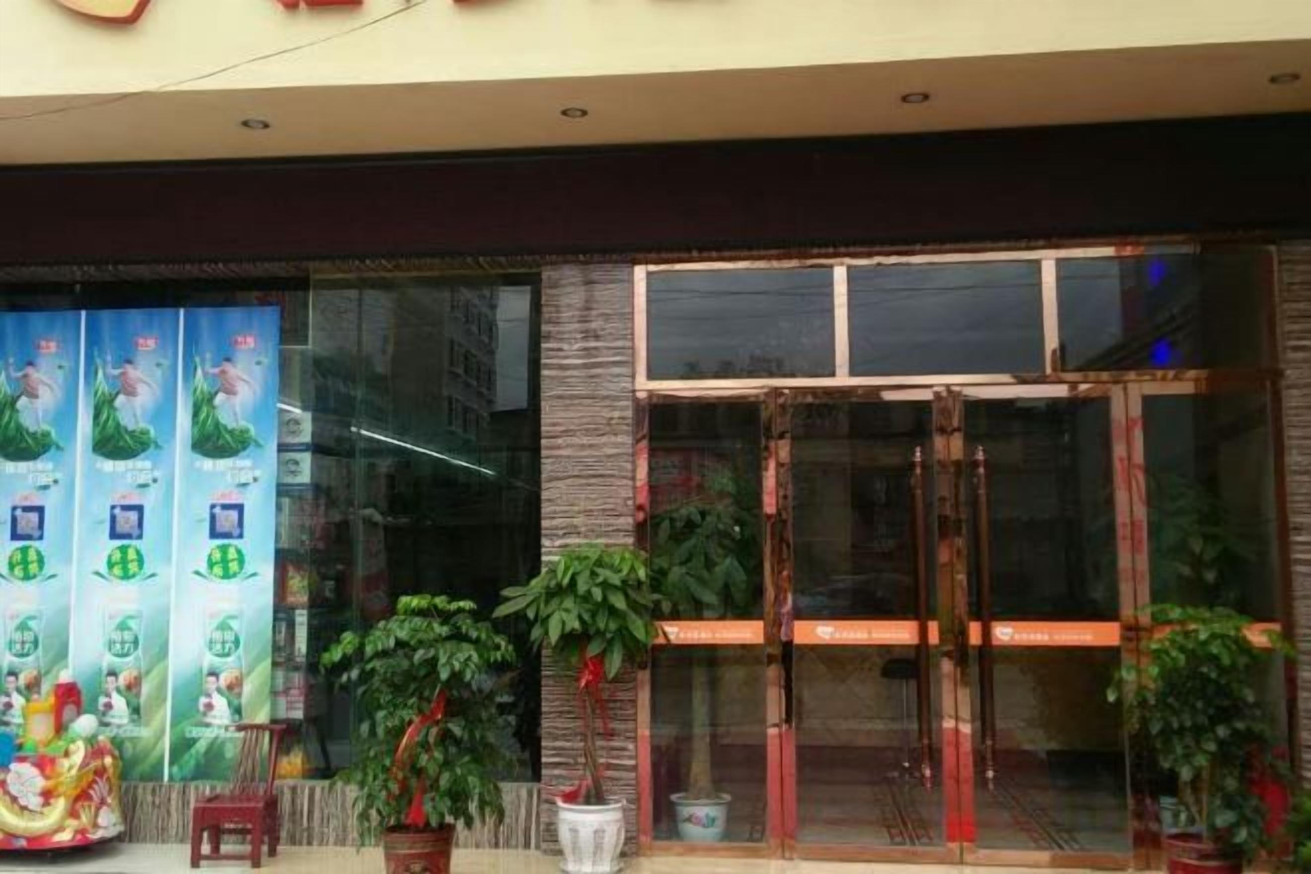 A building entrance with glass doors, potted plants, and a banner with text.