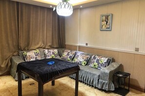 A living room with a sofa, a table, a chandelier, and a painting on the wall.