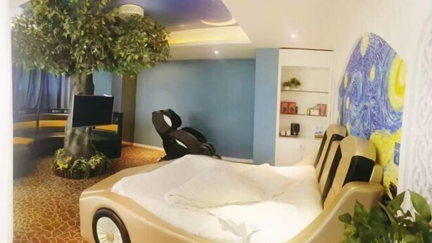 A room with a bed, a large tree, a bookshelf, and a wall painting. - Yimengshu Hotel (Lichuan)