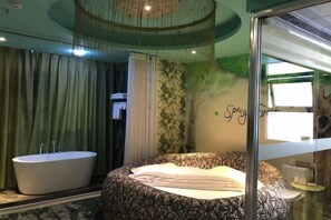 A room with a large bed, a bathtub, and a wall with a tree mural. - Yimengshu Hotel (Lichuan)