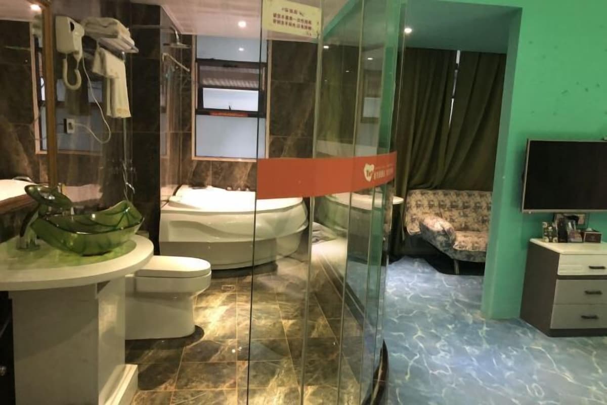 A bathroom with a glass bowl sink, a toilet, a bathtub, and a shower.