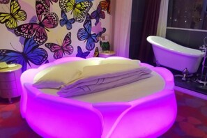 A bed with a unique design, a wall with a butterfly mural, and a white bathtub.