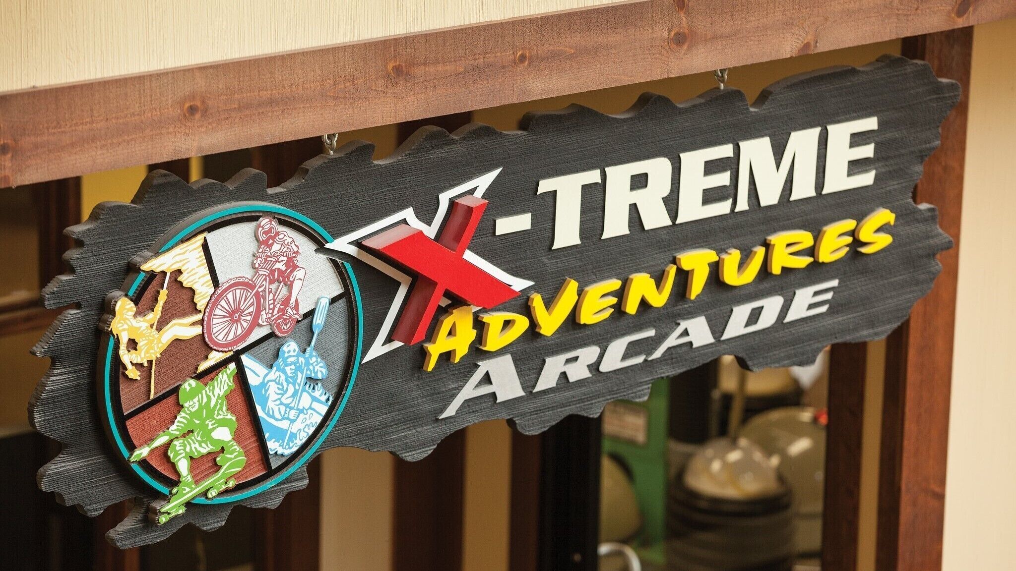 Une enseigne pour « X-TREME Adventures Arcade », avec un motif coloré en forme d’engrenage.