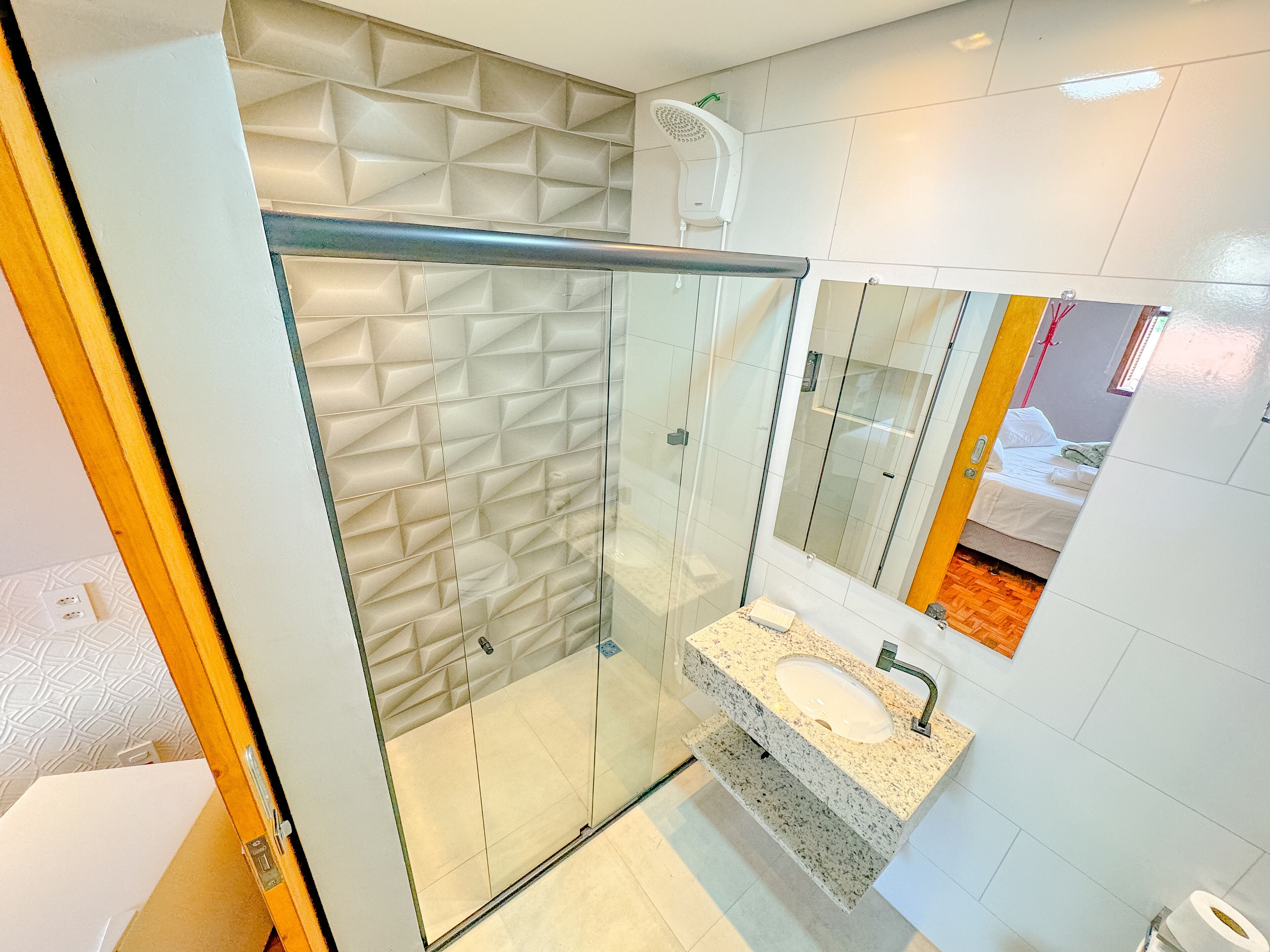 A modern bathroom with a glass-enclosed shower, a granite sink, and a large mirror.