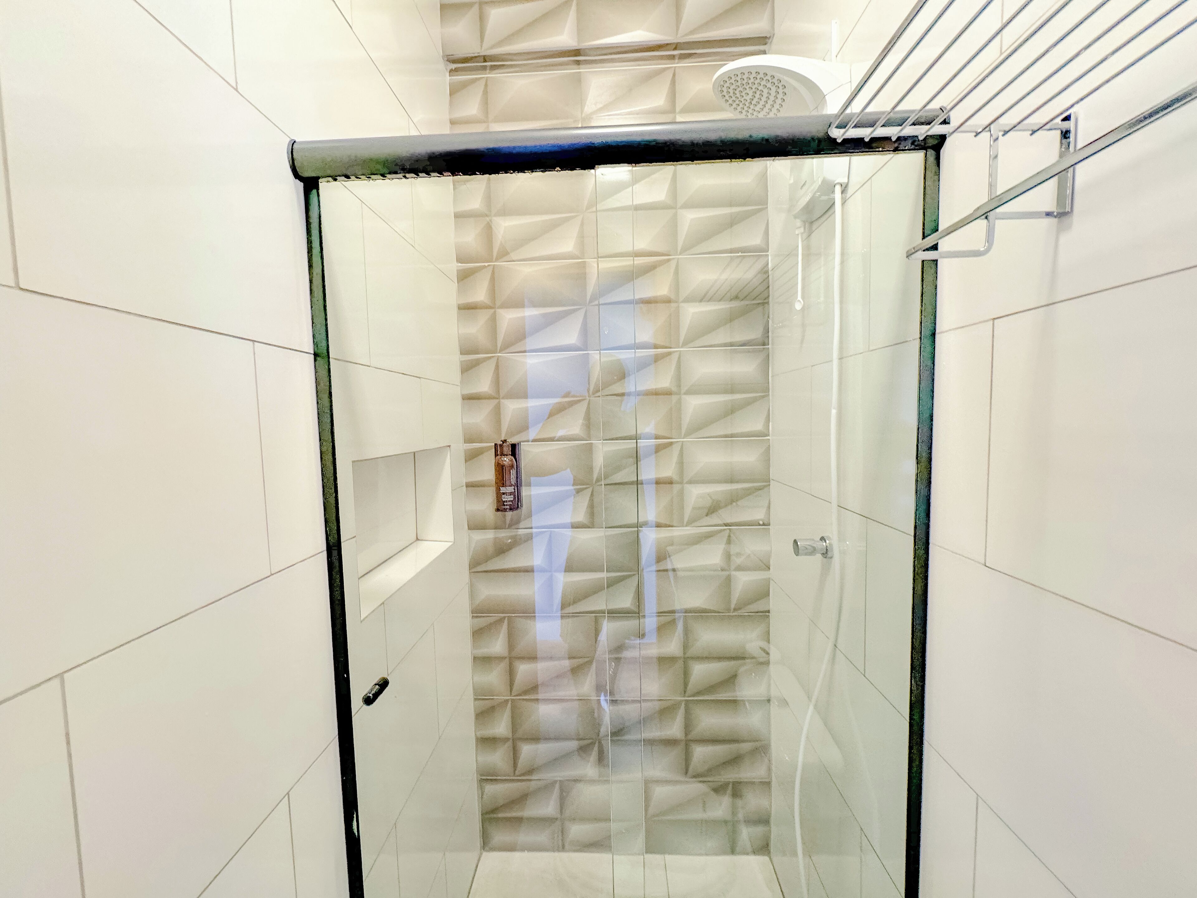 A modern shower with a geometric tile pattern and a glass door.