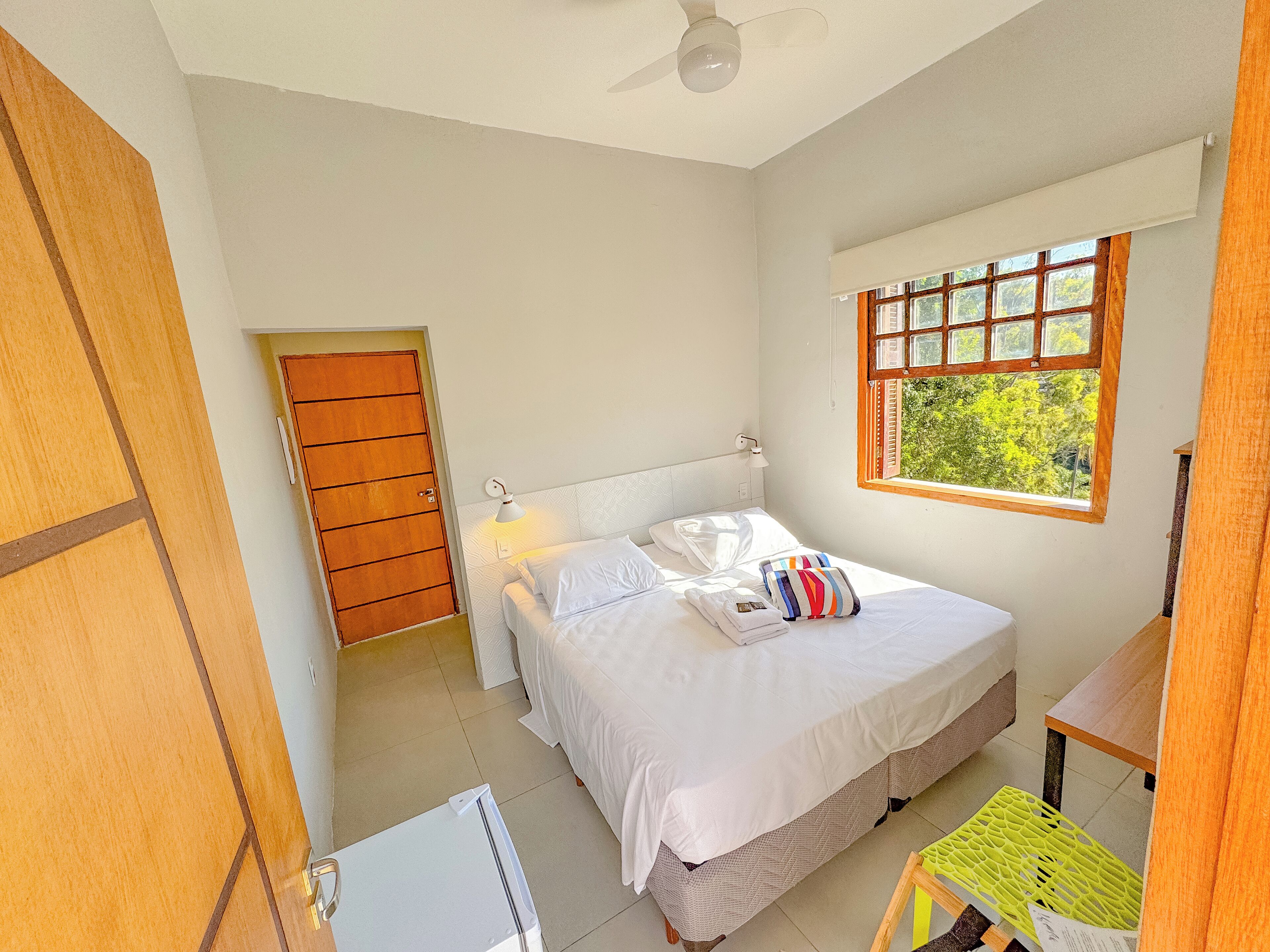 Une chambre à coucher avec un lit, une fenêtre, une porte et un ventilateur de plafond.