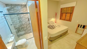 A bathroom with a glass shower enclosure, a toilet, and a sink. - Edifício Barros (Serra Negra)