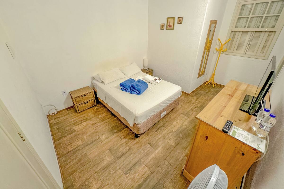 A small, clean room with a bed, a desk, a chair, and a window.