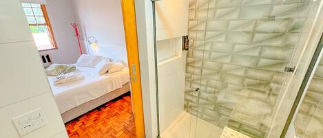 Un baño moderno con cabina de ducha de vidrio, un lavamanos blanco y suelo de madera.