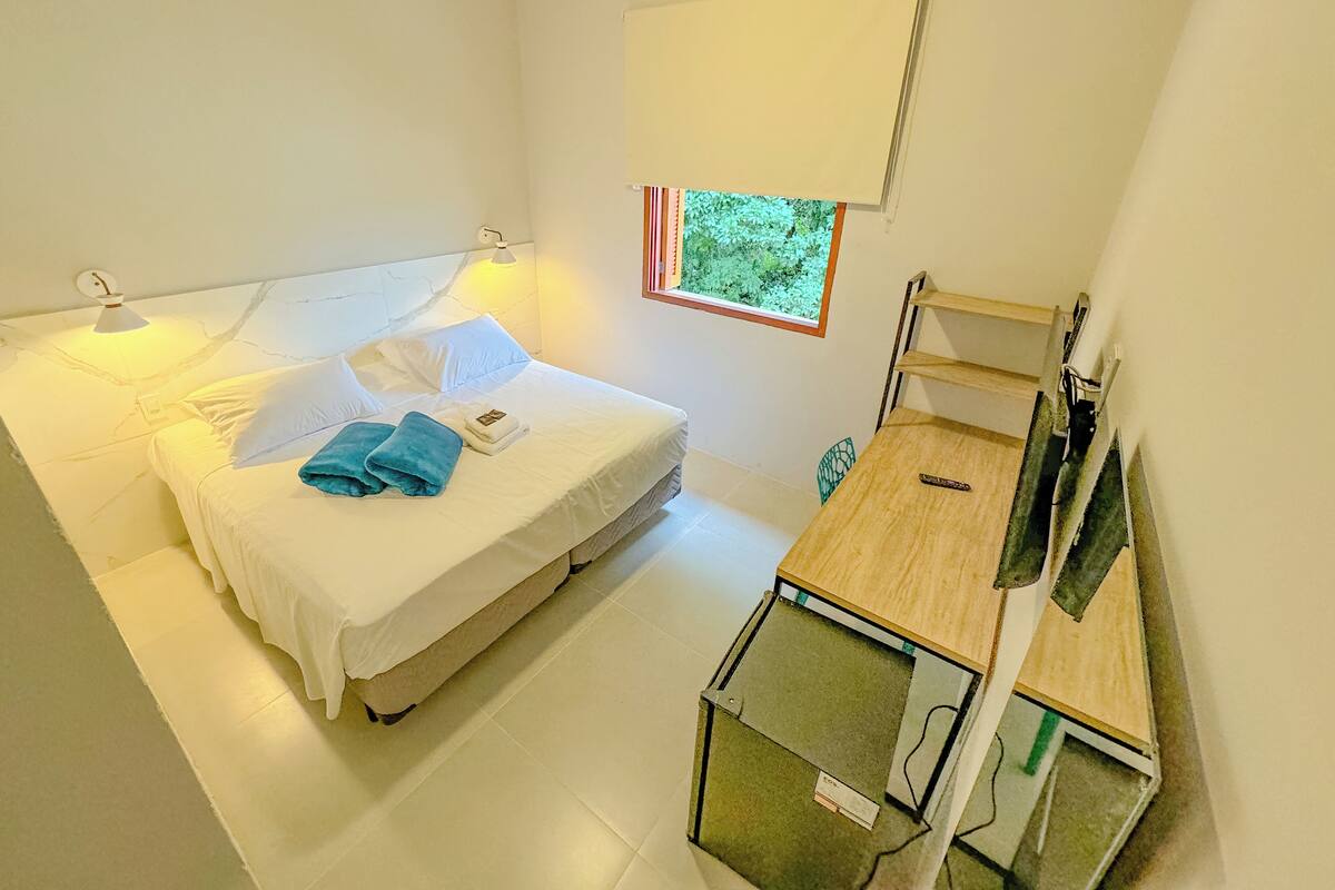 A bedroom with a bed, bedside table, and a small desk with a chair.