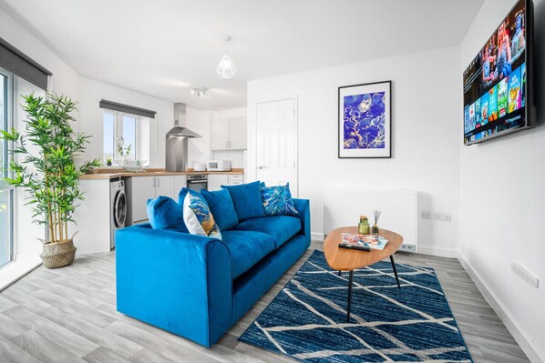 Una sala moderna con un sofá azul, una mesa de centro y un ventanal grande.