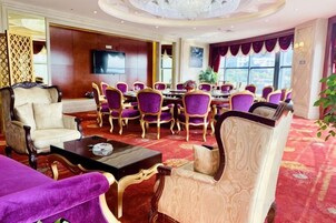 A hotel lobby with a dining area, a television, and a large window.