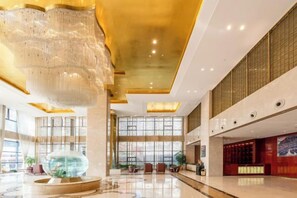 A spacious lobby with a large chandelier, a reception desk, and a seating area with chairs.