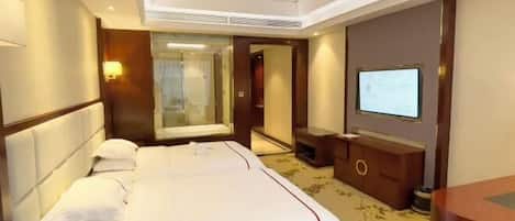 Una habitació d'hotel amb un llit gran, una televisió, una taula de nit i un mirall.